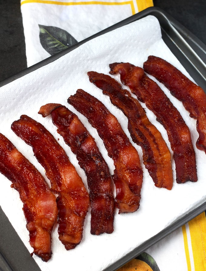 View of crispy and golden brown perfectly cooked bacon laying on a paper towel lined tray