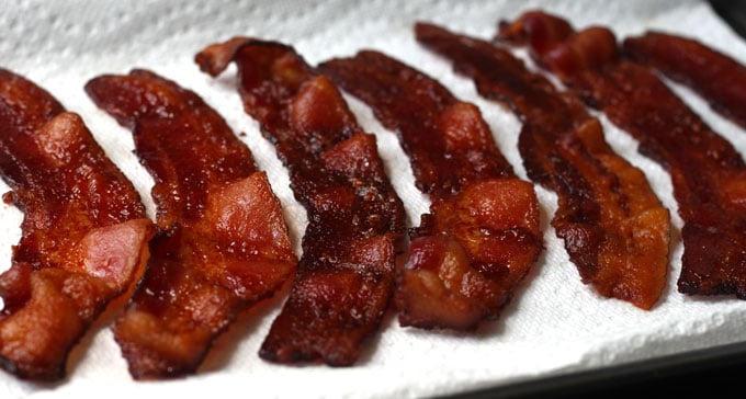 Side view of crispy bacon on a paper towel lined tray