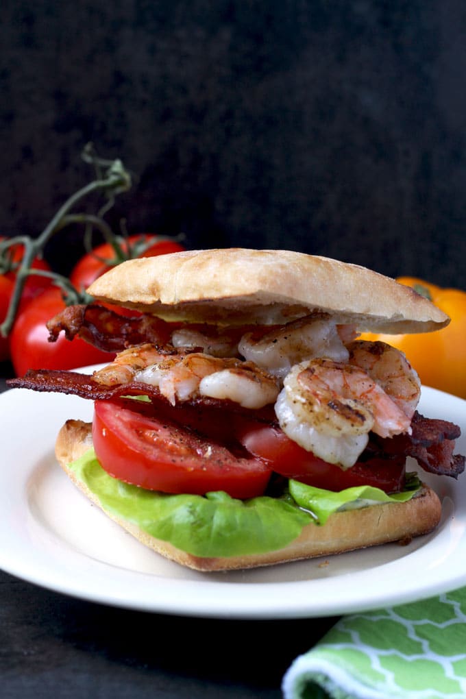 A sandwich with grilled shrimp in herb aioli with tomatoes, bacon and lettuce 