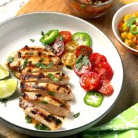 Sliced grilled chicken on a white plate.