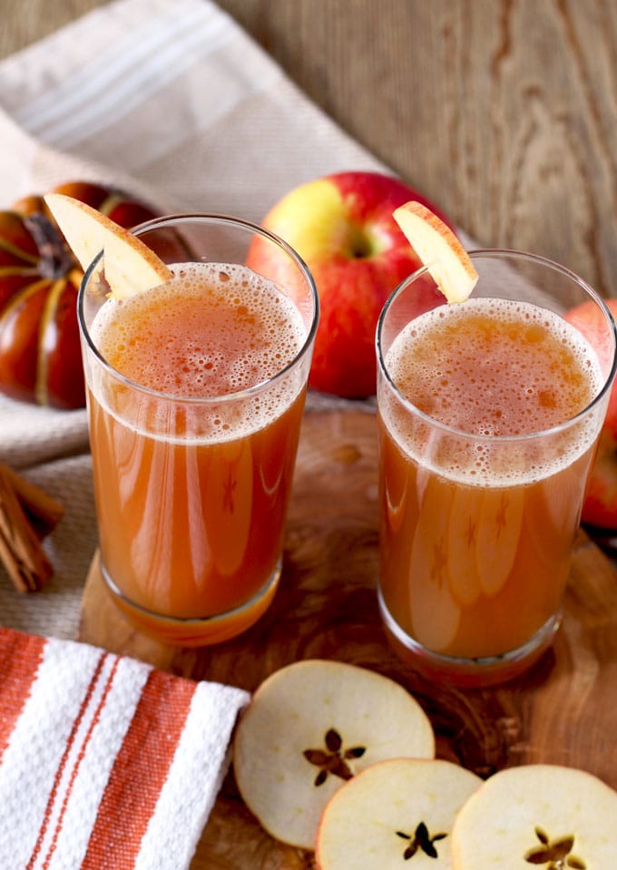 Two tall glasses with harvest shandy garnished with apple slices