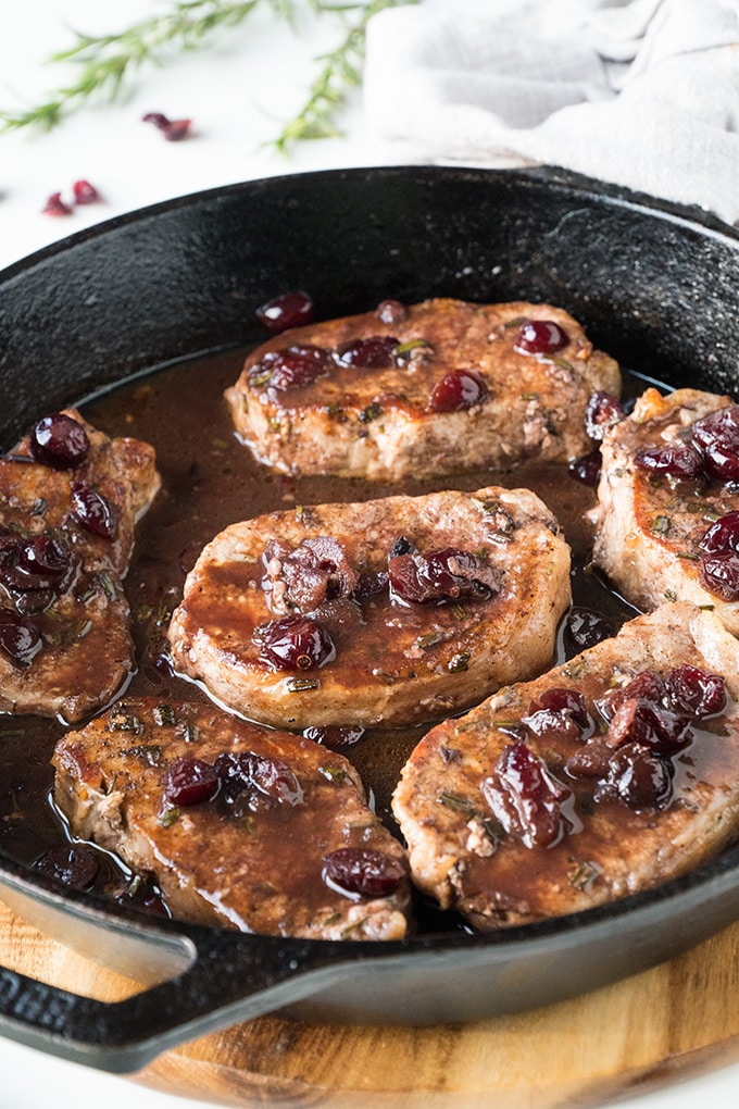 Pork chops with port wine and cranberries in a skillet.