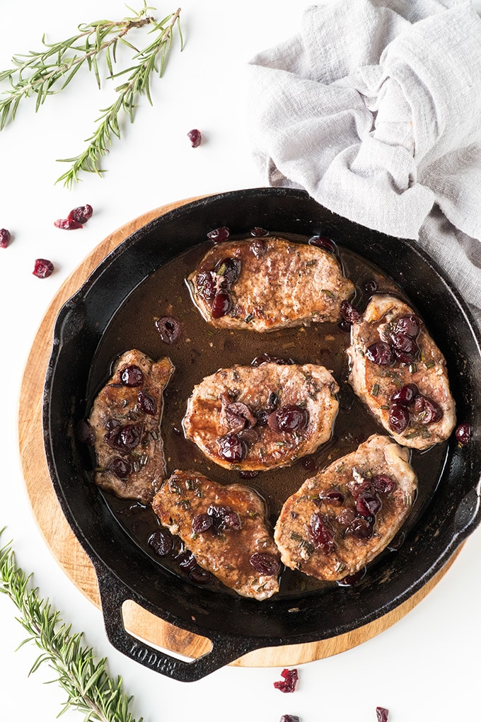 Top view of skillet pork chops topped with port wine and cranberries.