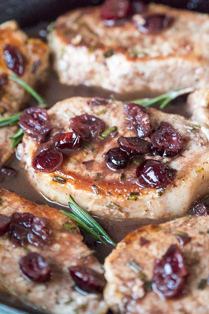 Skillet Pork Chops topped with cranberries and port wine in a skillet.