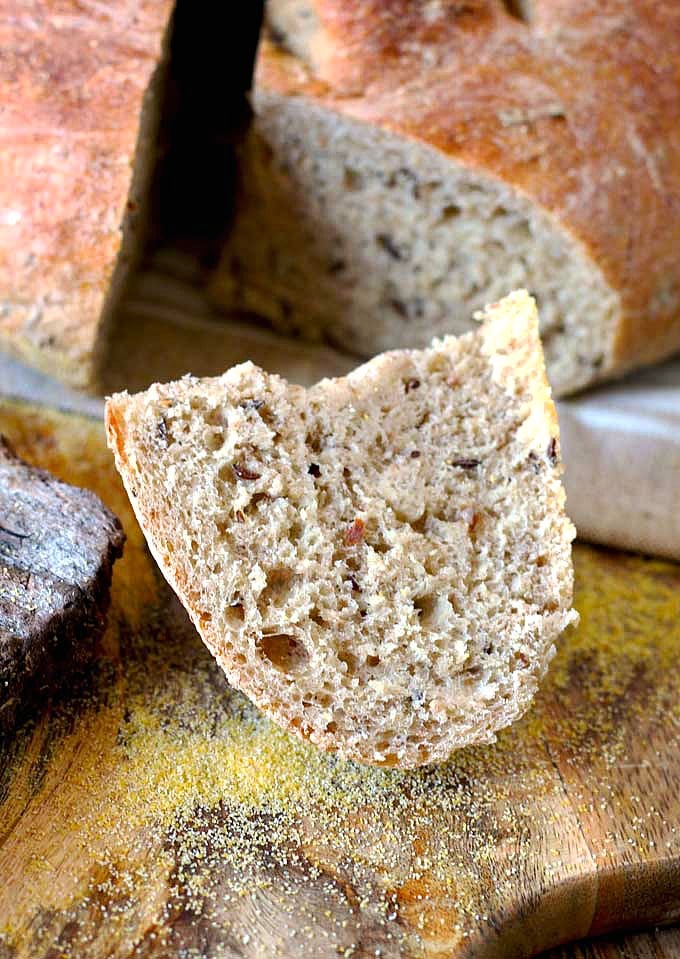 A piece of German Farmer's bread on a wooden cutting board.