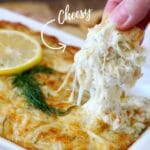 Pin with a photo of hot crab dip scooped with pita chips