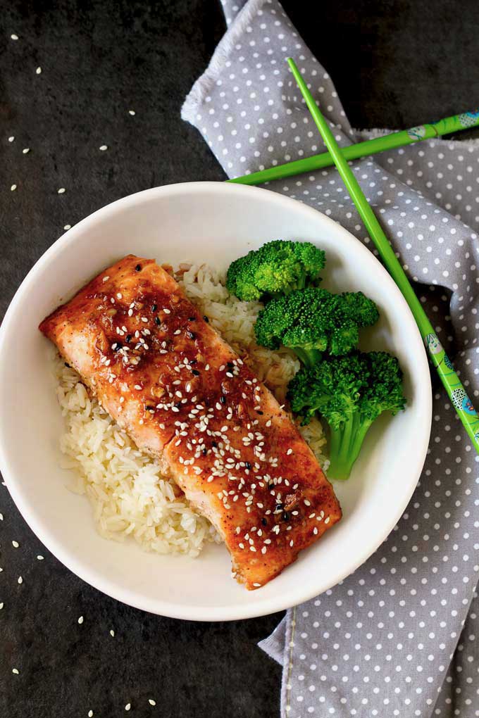 Top view of oven baked salmon with honey ginger glazed on a bed of rice served with broccoli. 