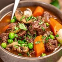 Beef stew with carrots, pearl onions, mushrooms and mushrooms in gravy served in a bowl.