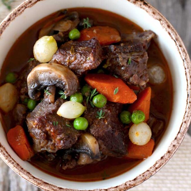 Beef Stew in Red Wine Sauce, tender beef cubes cooked in red wine with onions, garlic, carrots, mushrooms, peas, thyme and bay leaves. The result is a thick, rich, flavorful and out of this world delicious stew. You can cook it in the oven or in the crockpot!
