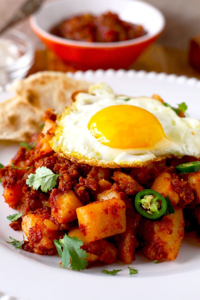 Close-up of Potatoes and Chorizo Hash served on a plate and topped with a fried egg, sunny side up.