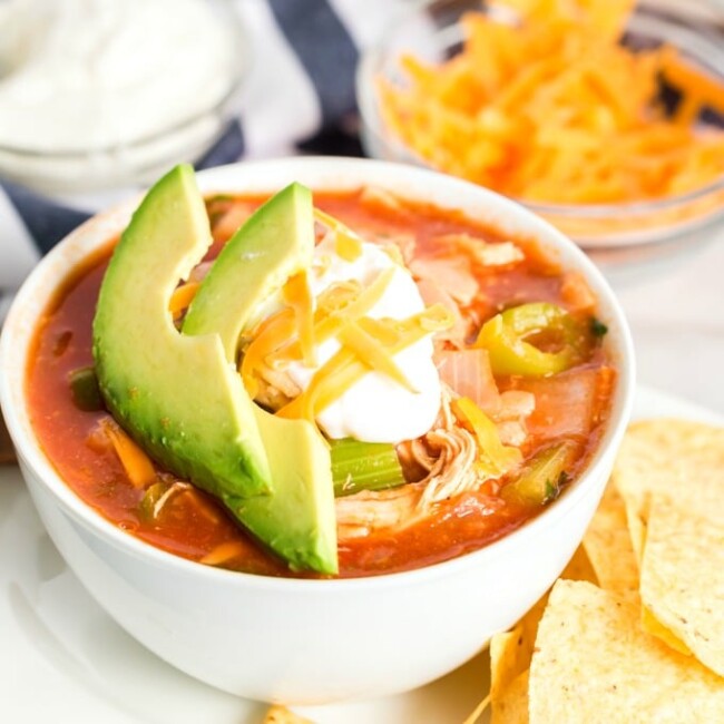 Tortilla soup with chicken in a white bowl.