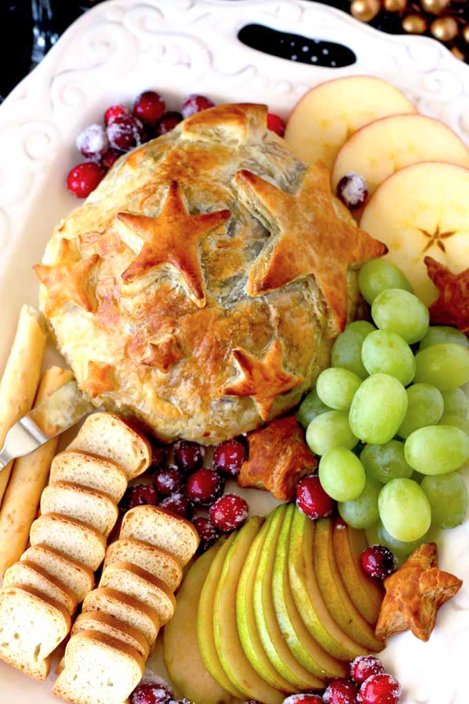 Overhead view of Baked Brie with Cranberries served with fruit and crackers.