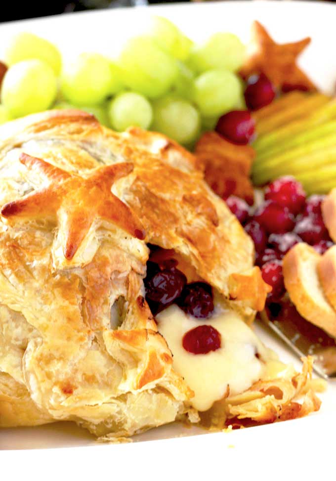 Close up of melted baked Brie served with fruit and crackers
