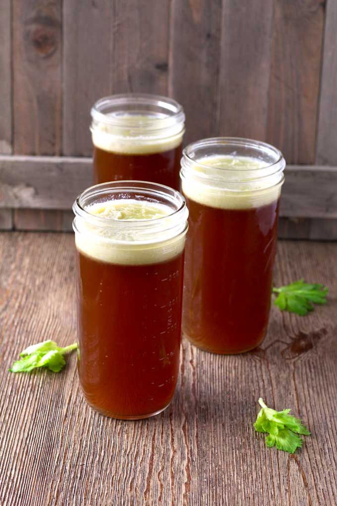 Picture here three jars filled with slow cooker beef bone broth. On the top, you can see a layer of fat that can be removed after the broth is cold