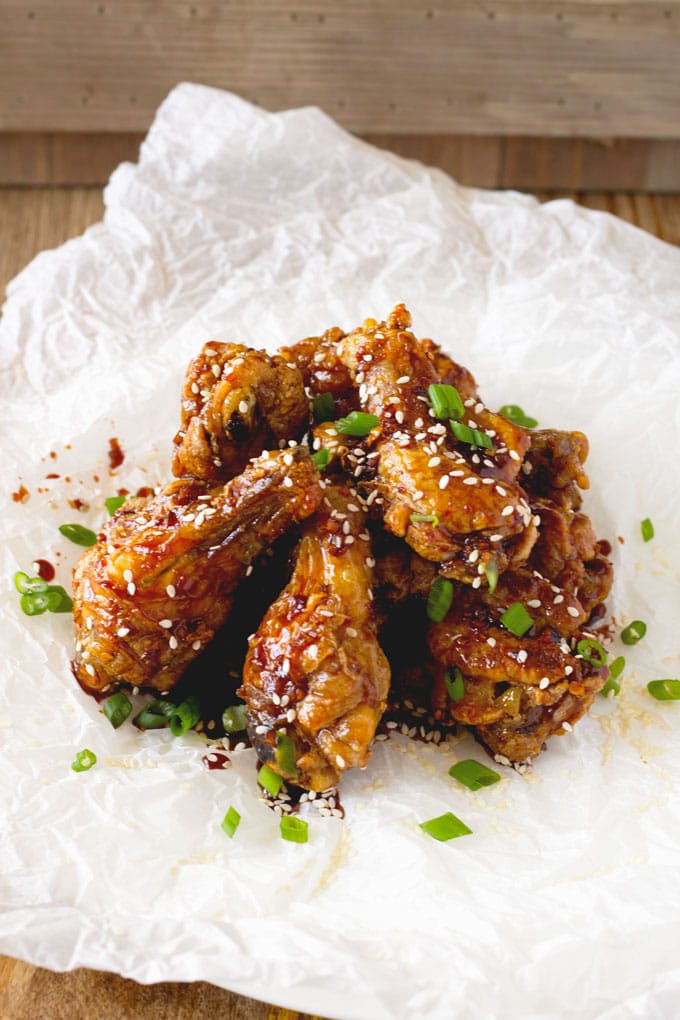 A pile of Chicken Wings garnished with sesame seeds and sliced scallions.