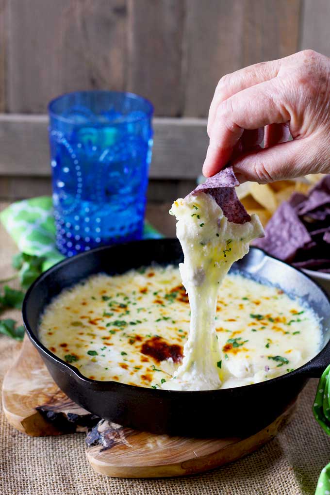 Melty quedo fundido dip scooped with a tortilla chip.