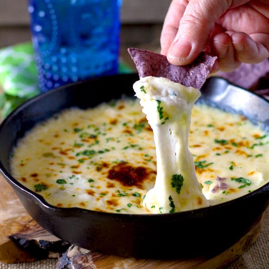 Melty and gooey Queso Fundido served from a cast iron skillet