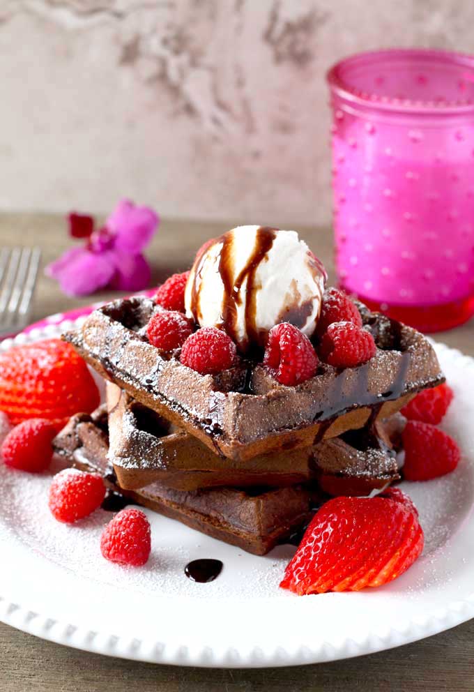 A stack of Double Chocolate Waffles Recipe topped with ice cream and berries.