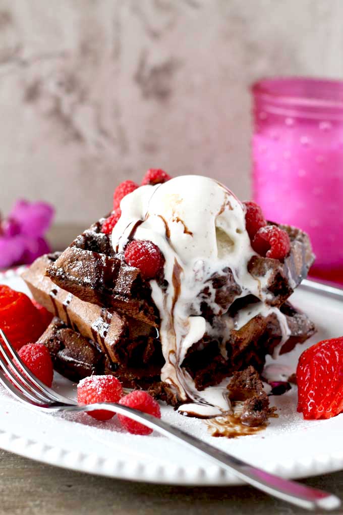 A scoop of vanilla ice cream melting on top of a stack of Double Chocolate Waffles