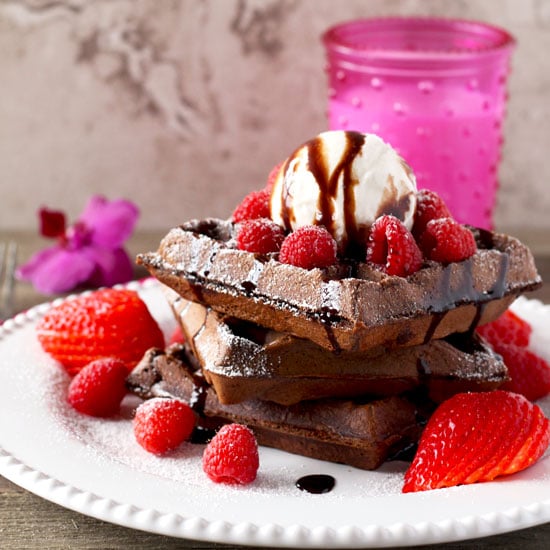 Stack of Double Chocolate Waffles topped with ice cream and berries on a white plate.