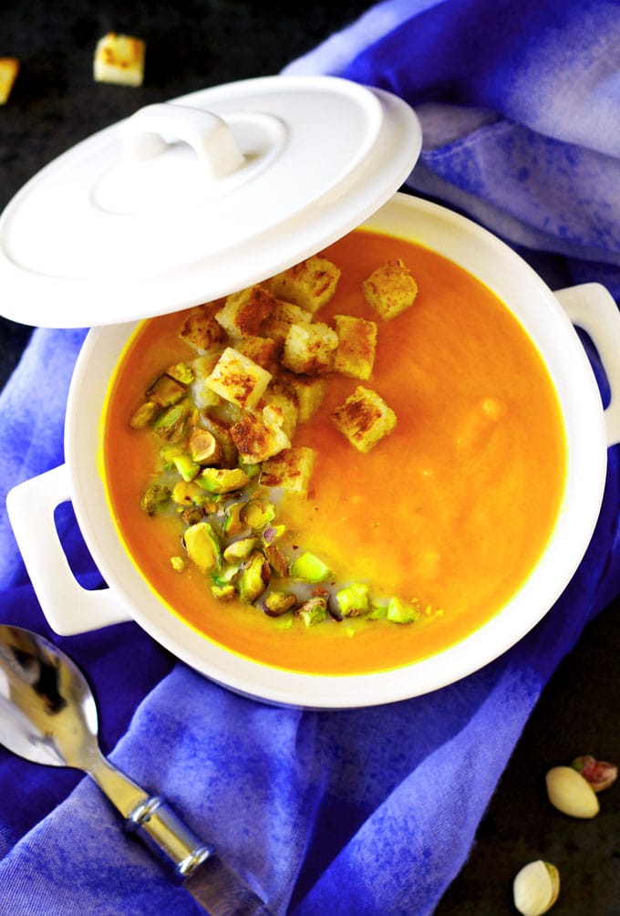 Close up view of a white pot filled with carrot soup