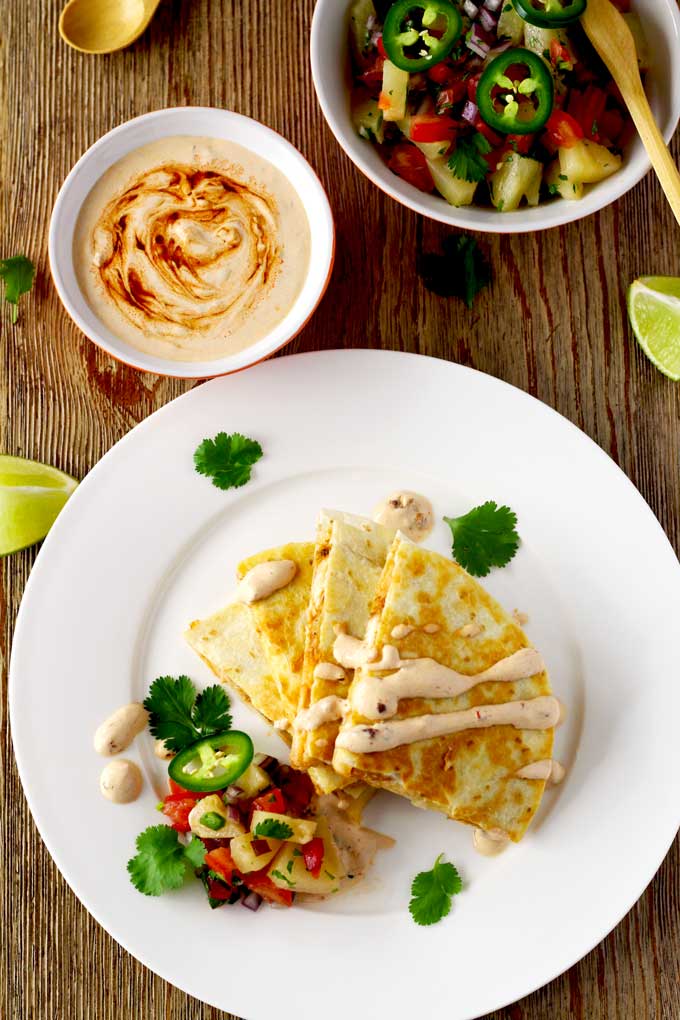 This easy to make Tex Mex inspired BBQ Chicken Quesadilla with Smoked Gouda Cheese is packed with super flavorful chicken and gooey cheese. Served with a delicious and fruity pineapple salsa and topped with a spicy and smoky Chipotle Crema! Let's sum that up in one word ~ Amazing!