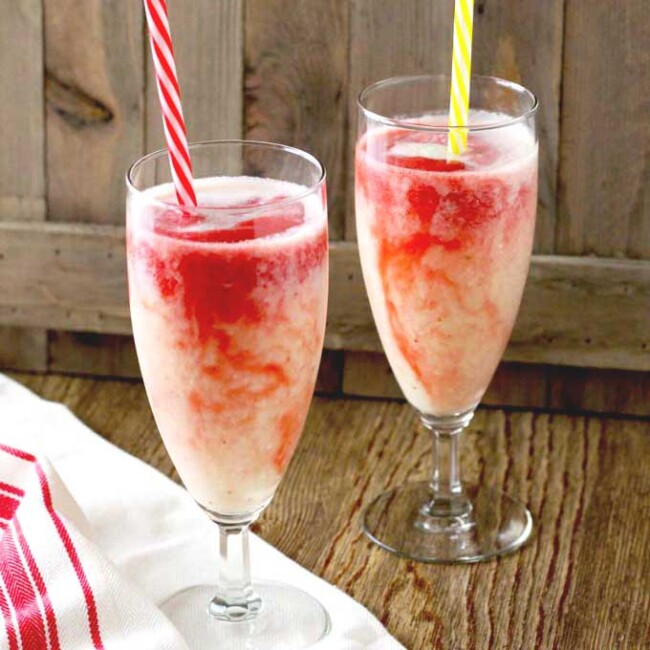 Two glasses of Hawaiian Lava Flow Cocktail with straws on a wooden surface