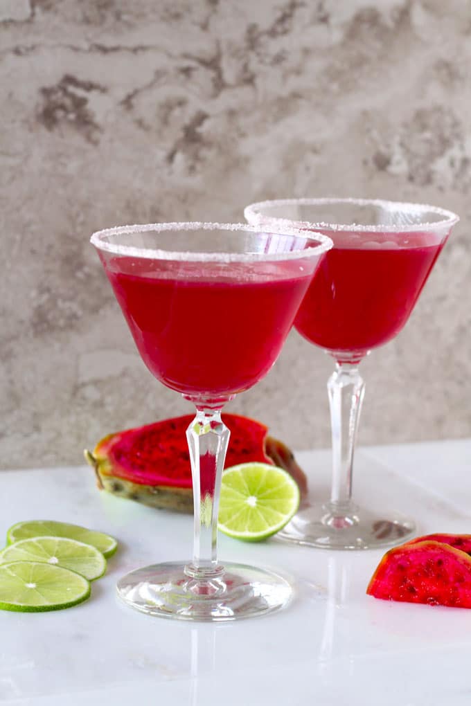 Two bright pink Margarita glasses with sugar on the rim.