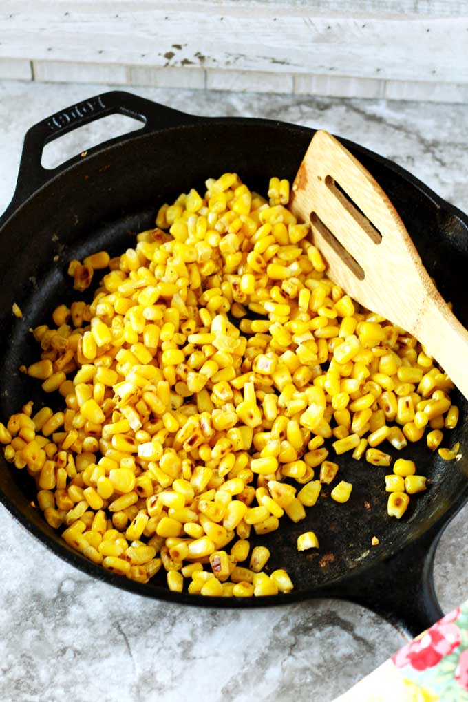 Corn kernels roasting in a cast iron skillet.
