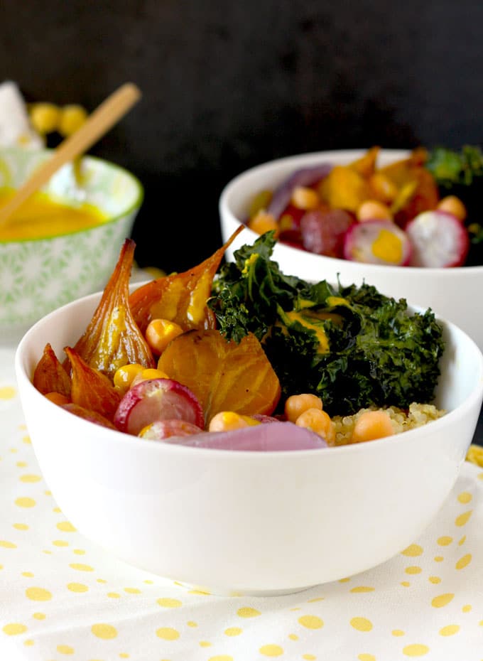 A white bowl with quinoa, caramelized radishes, golden beets, roasted kale and chickpeas.