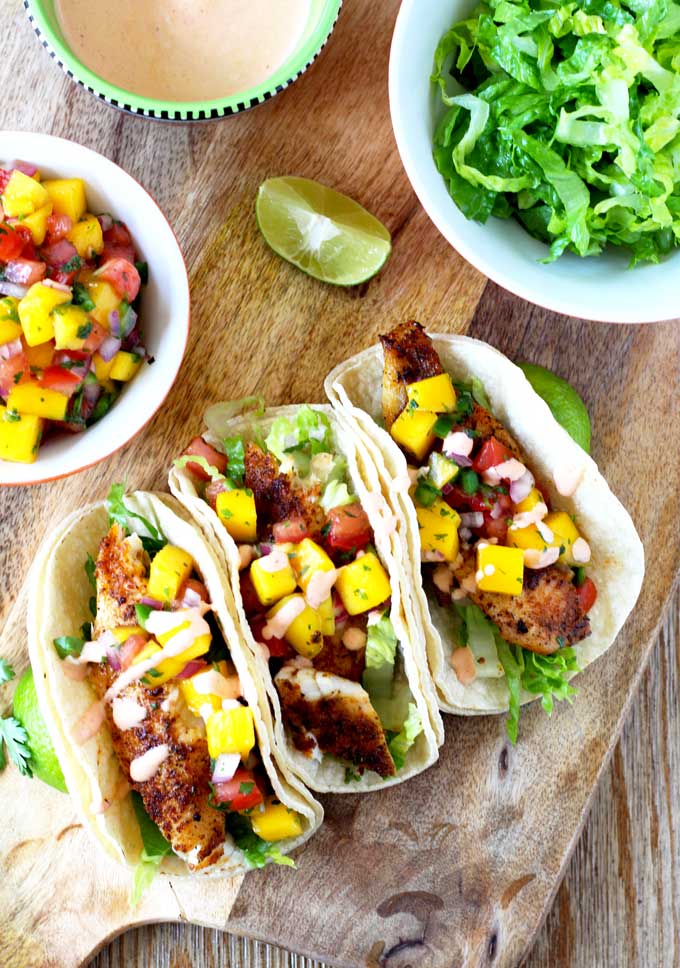Full flavored, healthy and easy to make Blackened Fish Tacos with Mango Salsa and Sriracha Aioli. Fish fillets coated in a Cajun inspired spice mix served in warm tortillas and topped with a fresh and tasty mango salsa. Finish it up with a drizzle of creamy and spicy sriracha aioli for the best tacos ever!!!