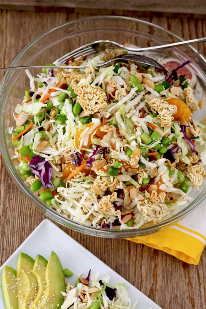 Ramen salad with shredded cabbage and mandarin oranges in a glass salad bowl