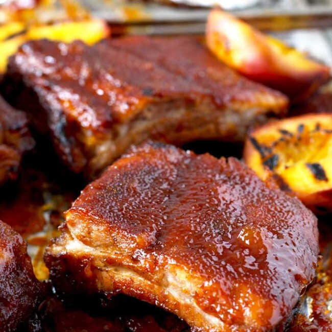 These Mouthwatering Bourbon and Peach BBQ ribs are seasoned with a simple spice rub mix and cooked in the oven until fall-off-the-bone tender. Smothered in a lip-smacking Bourbon and Peach BBQ sauce, these ribs are easy, delicious and foolproof!