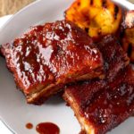 These Mouthwatering Bourbon and Peach BBQ ribs are seasoned with a simple spice rub mix and cooked in the oven until fall-off-the-bone tender. Smothered in a lip-smacking Bourbon and Peach BBQ sauce, these ribs are easy, delicious and foolproof!