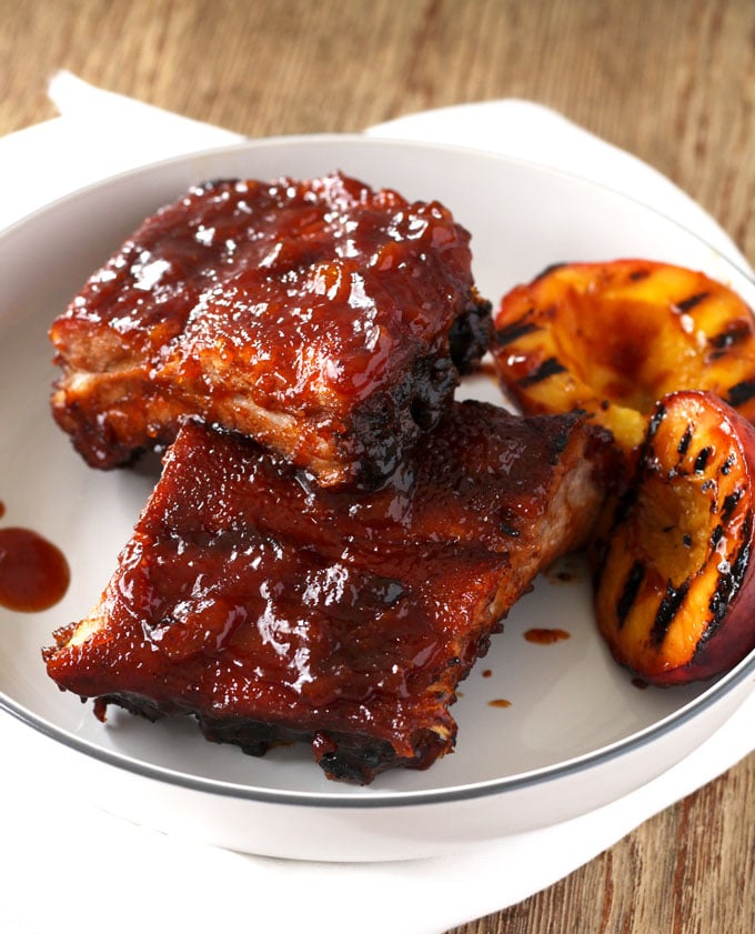 A serving of BBQ ribs in the oven smothered with Bourbon Peach BBQ sauce on a plate
