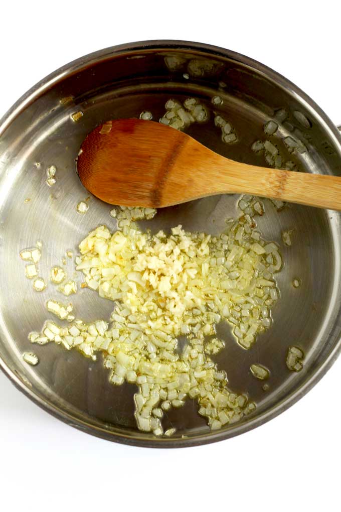 Garlic added to sauteed onions in a pot.