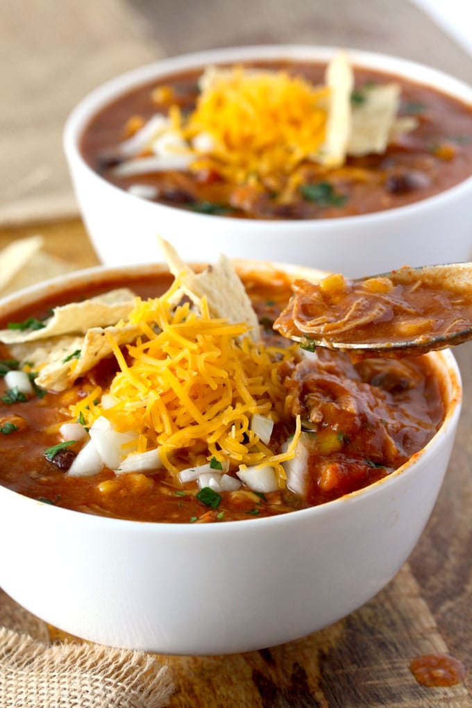 A spoon scooping Chicken Enchilada soup from a bowl.
