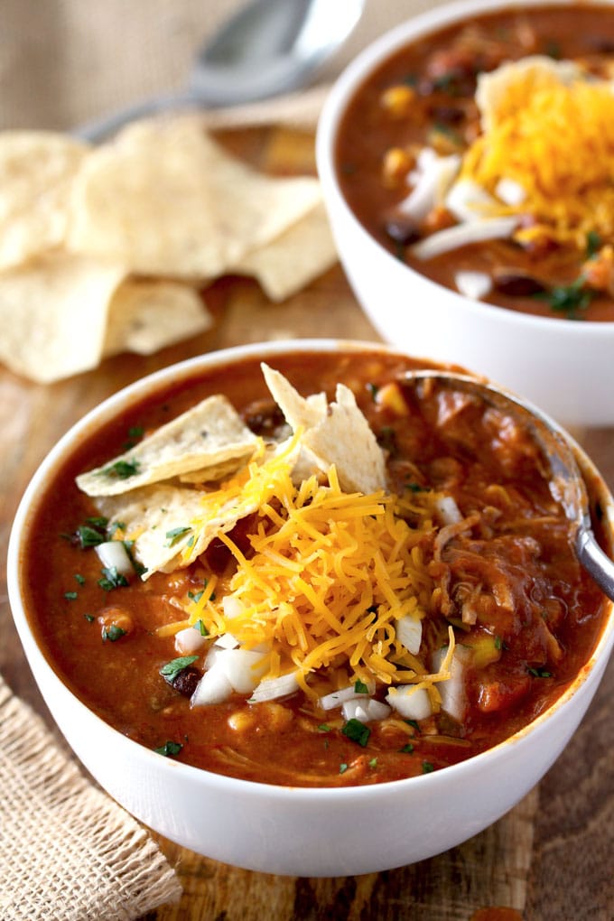 A bowl of Chicken Enchilada Soup with toppings in a white bowl