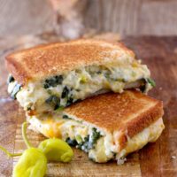 Buttery and toasty bread with an incredibly gooey and delicious filling. This easy Spinach and Artichoke Dip Cheese Melt is everything a grilled cheese sandwich should be and then some!! The addition of peperoncini adds brightness and zing to this delicious sandwich!