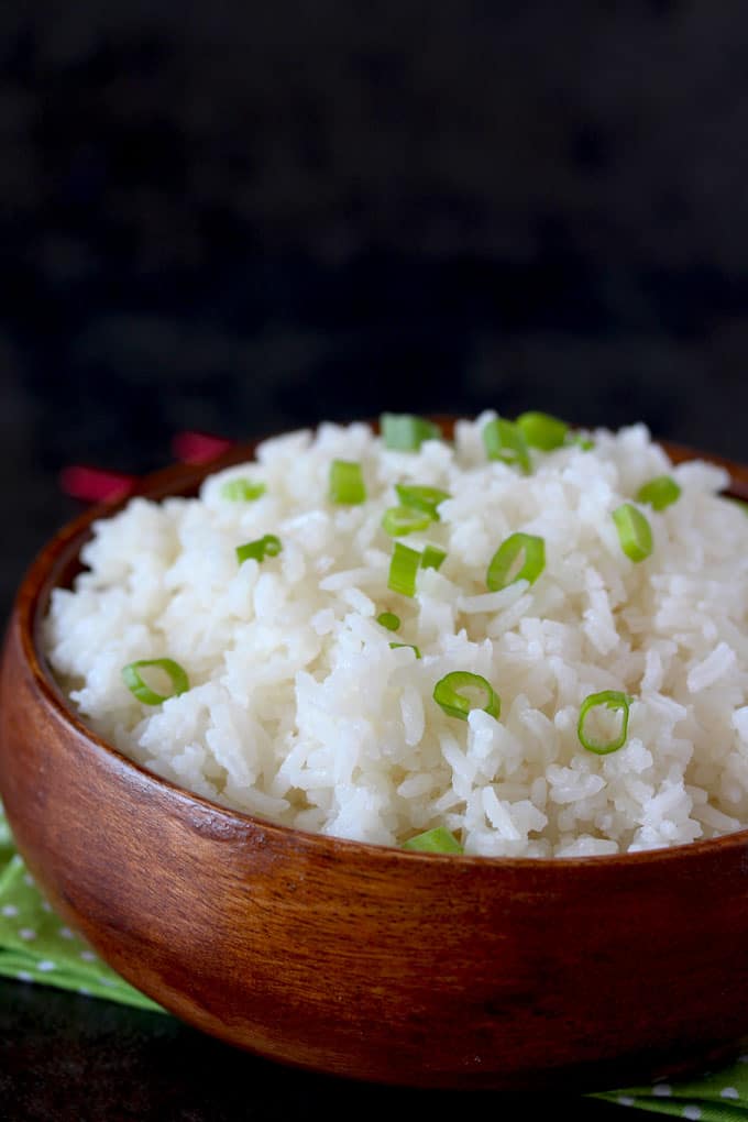 Close-up view of Jasmine rice with Gingered and Lemongrass in a wooden bowl garnished with thinly sliced green onions