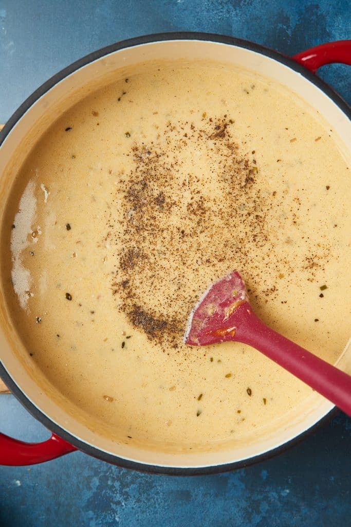 Stirring in ground black pepper into beer cheese soup