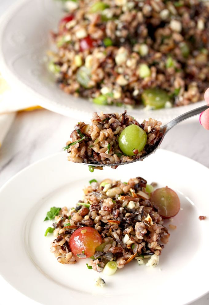 Spoonful of Wild Rice Salad Salad with Citrus Miso Vinaigrette shown. In the background a bowl of Wild Rice Salad