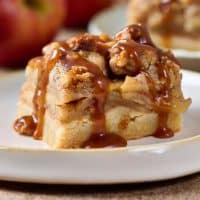 Close up side view of an apple pie bar with a pecan crumble and drizzled with salted caramel