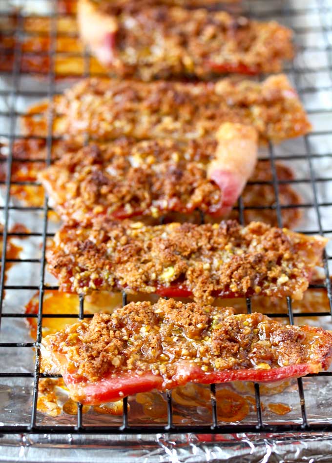 Bacon slices topped with brown sugar and nuts on a cooling rack.