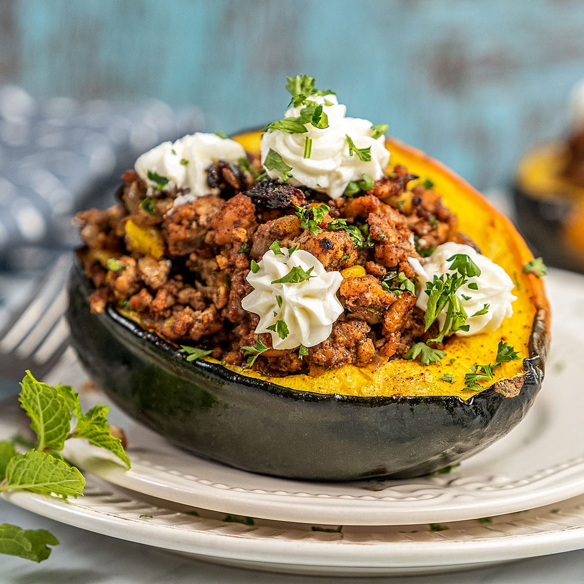 Stuffed acorn squash topped with whipped cheese on a plate