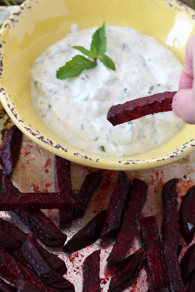 View of a roasted beet been dipped into creamy yogurt dip.