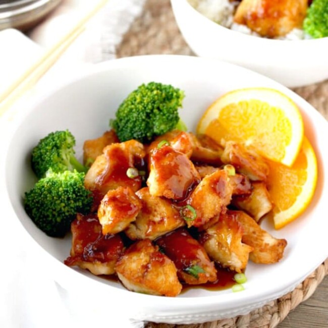 A white bowl filled with orange chicken and broccoli