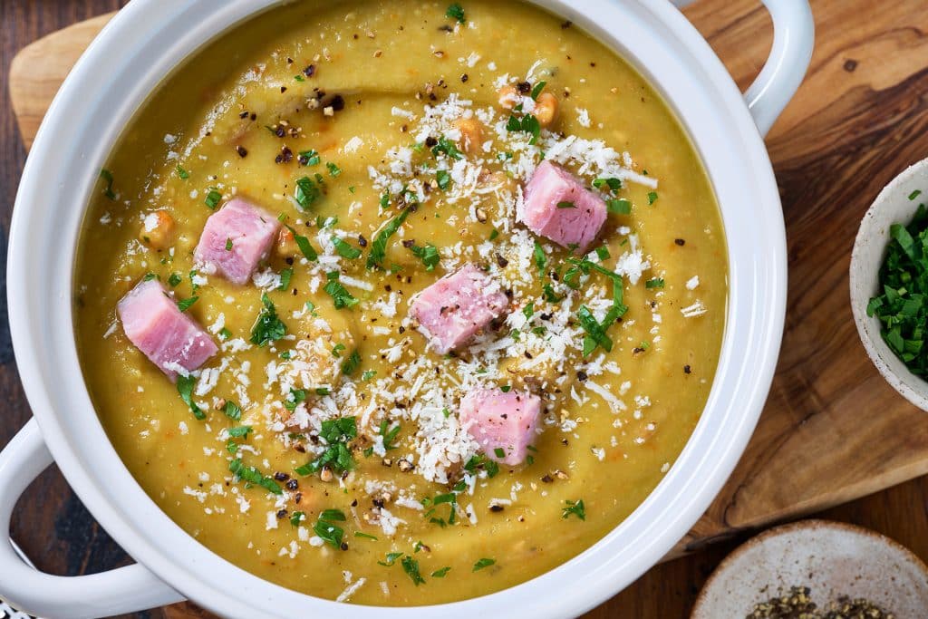 close top view of split pea soup garnished with ham cubes and parmesan cheese