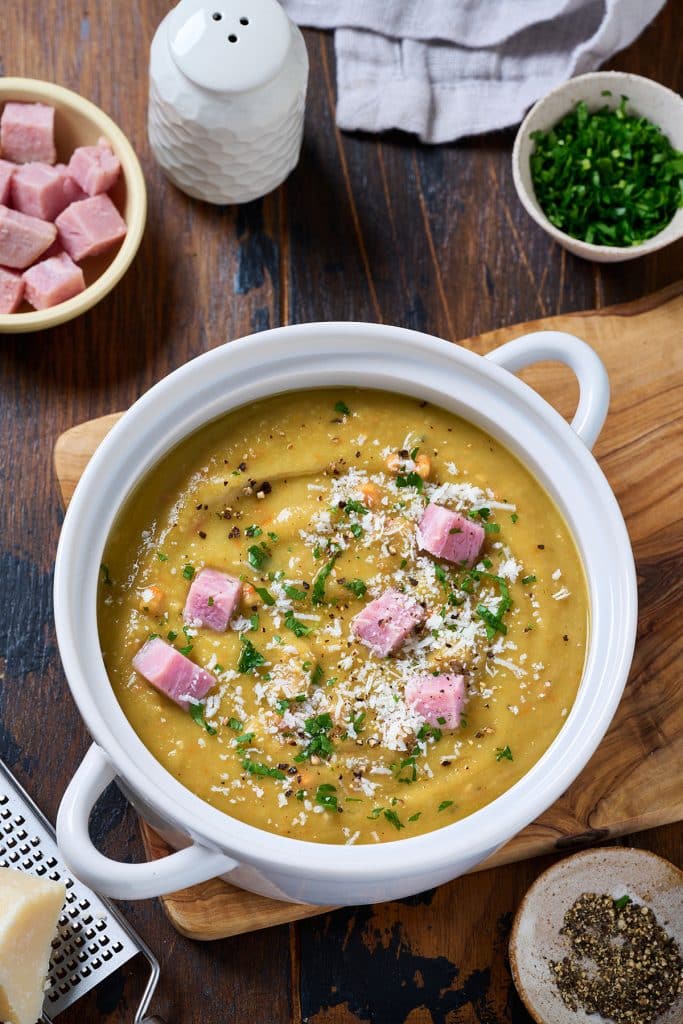 top view of a split pea soup with ham cubes in a white serving bowl