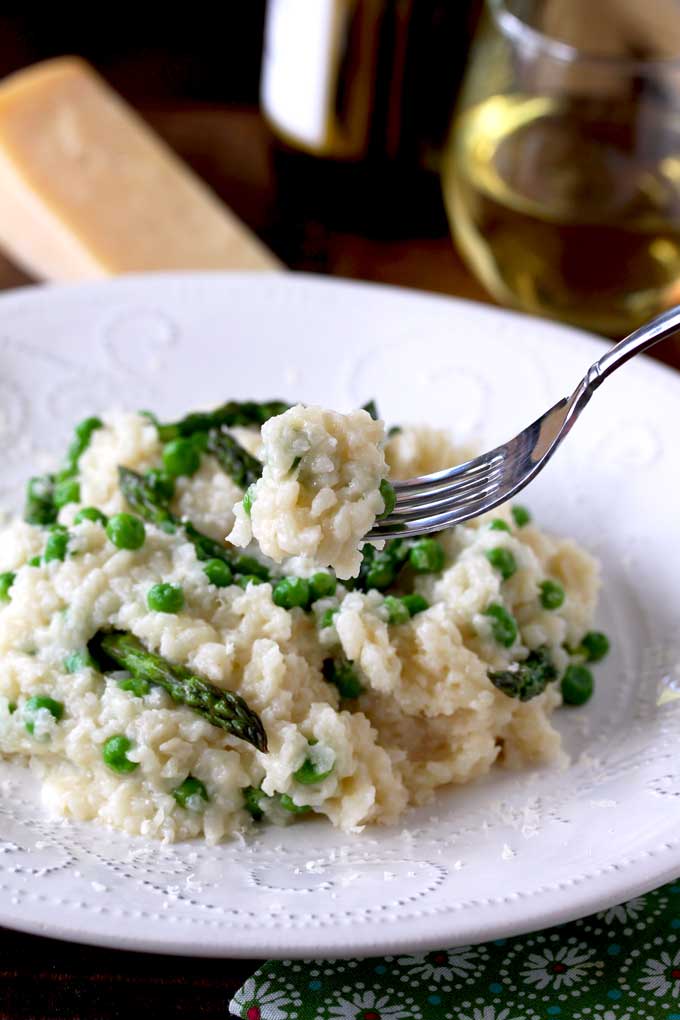 Close up view of a fork scooping out some creamy Parmesan, Peas and Asparagus Risotto
